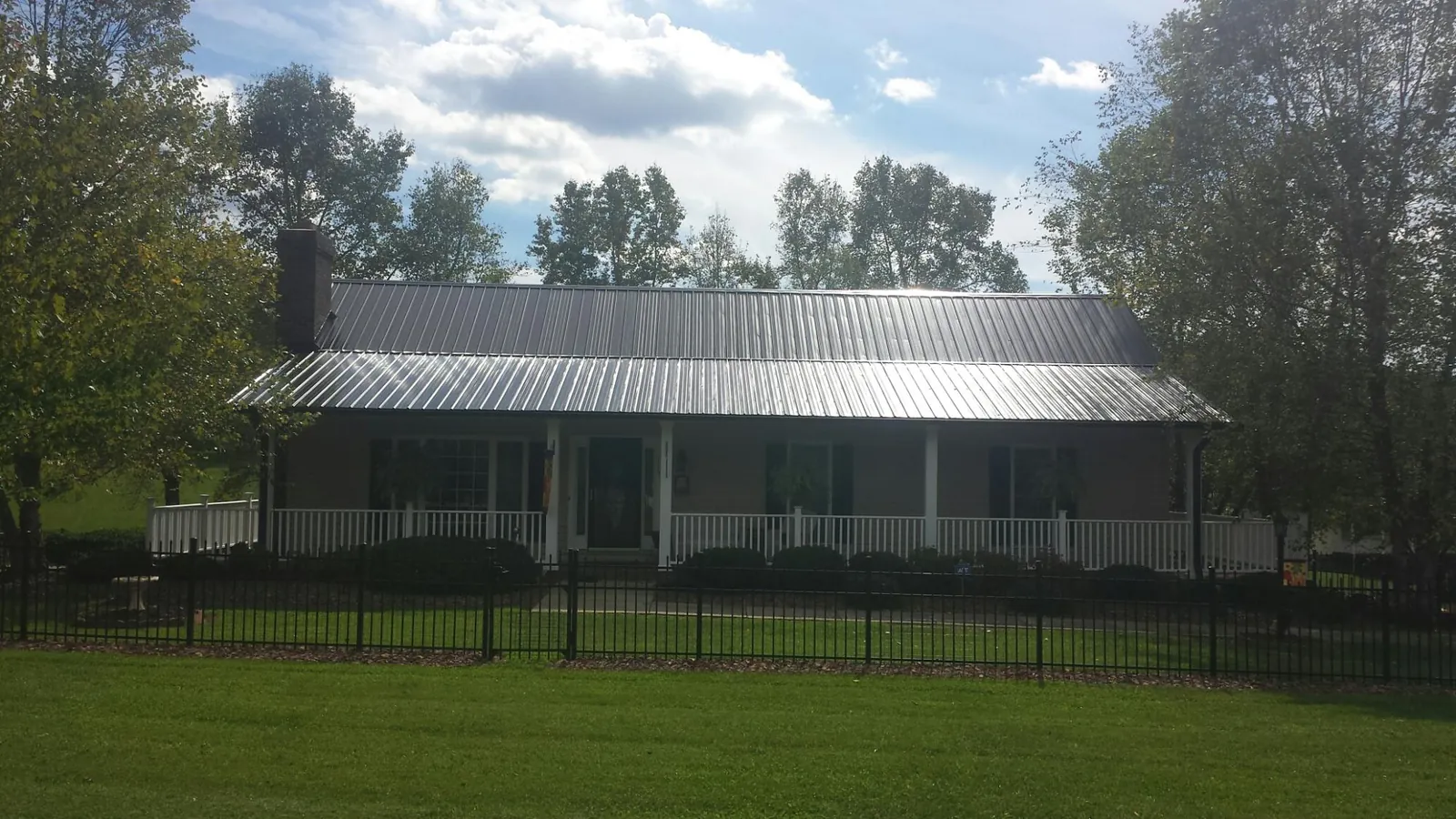 Gray metal roof on a brick ranch with a full width front porch — Gutter Guard Installation work by our crew in Mount Morris
