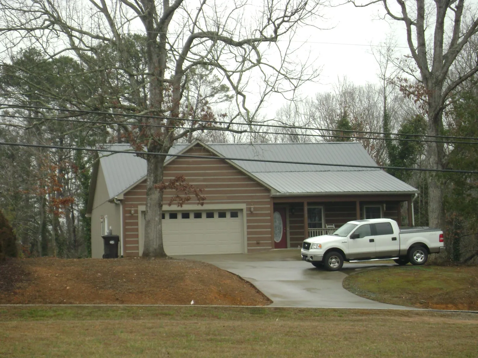 Gray metal roof on a log sided house with an attached two car garage in Mount Morris