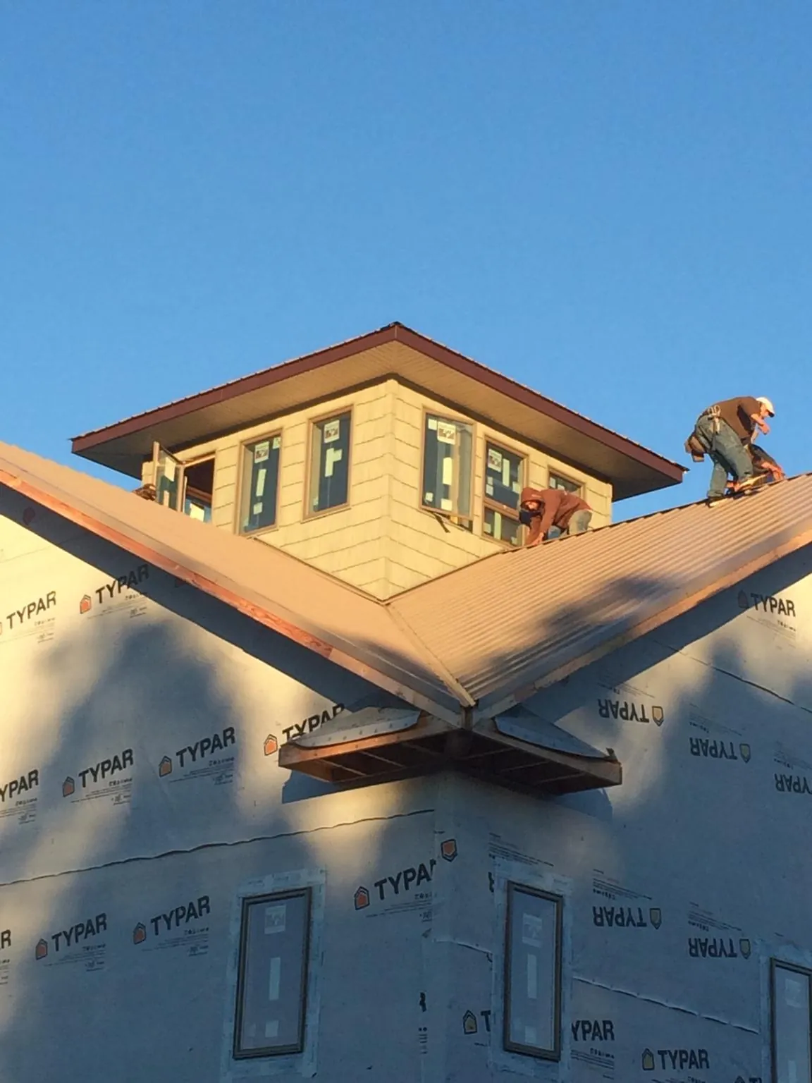 Roofers working around a rooftop cupola on a new metal roof at sunset — Roof Waterproofing in Mount Morris by Roofing Brothers